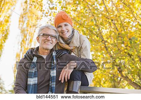 Stock Image - Older Caucasian couple smiling under autumn trees. Fotosearch