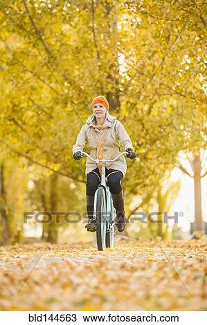 Older Caucasian woman riding bicycle on autumn leaves View Large Photo Image Stock Image - Older Caucasian woman riding bicycle on autumn leaves. Fotosearch