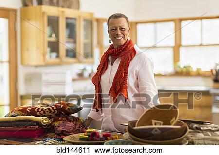 Stock Image - Older mixed race woman smiling in home office. Fotosearch