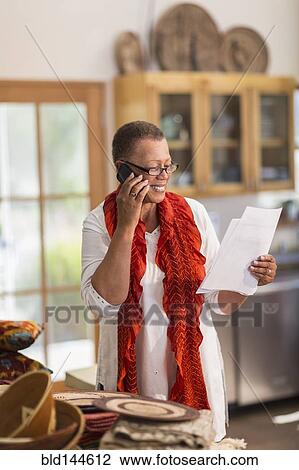 Older mixed race woman talking on telephone in home office View Large Photo Image Stock Image - Older mixed race woman talking on telephone in home office. Fotosearch