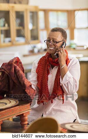 Older mixed race woman talking on telephone in home office View Large Photo Image Stock Photo - Older mixed race woman talking on telephone in home office. Fotosearch