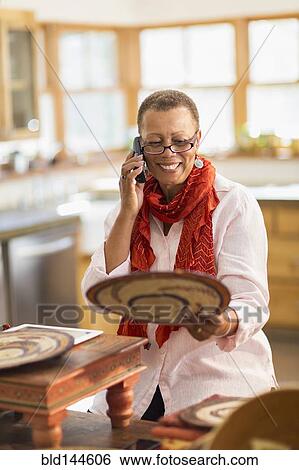 Older mixed race woman talking on telephone in home office View Large Photo Image Stock Photograph - Older mixed race woman talking on telephone in home office. Fotosearch