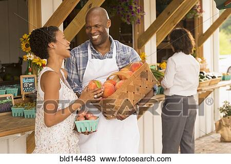 Stock Image - People laughing at farmers market. Fotosearch