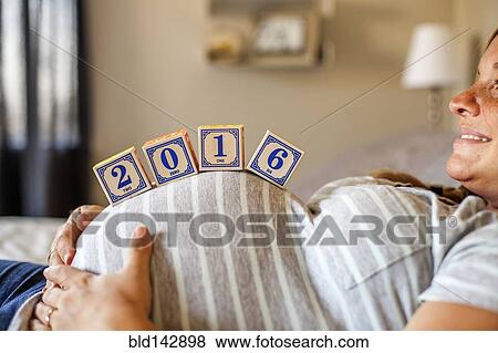 Pregnant Caucasian woman balancing wooden blocks on her stomach in bed View Large Photo Image Stock Photo - Pregnant Caucasian woman balancing wooden blocks on her stomach in bed. Fotosearch