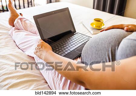 Pregnant Caucasian woman using laptop in bed View Large Photo Image Picture - Pregnant Caucasian woman using laptop in bed. Fotosearch