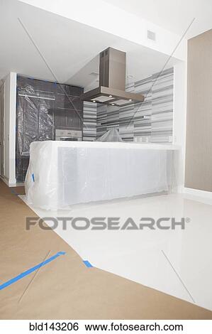 Stock Photograph - Protective plastic and paper tarps in kitchen under renovation. Fotosearch