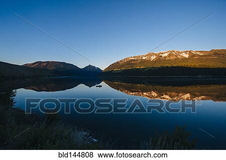 Remote mountains and blue sky reflected in still lake View Large Photo Image Stock Photo - Remote mountains and blue sky reflected in still lake. Fotosearch
