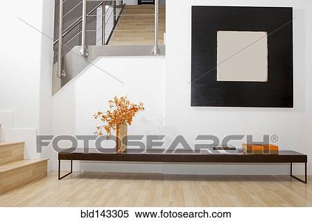 Stock Photography - Side table, wall art and stairs in modern front room. Fotosearch