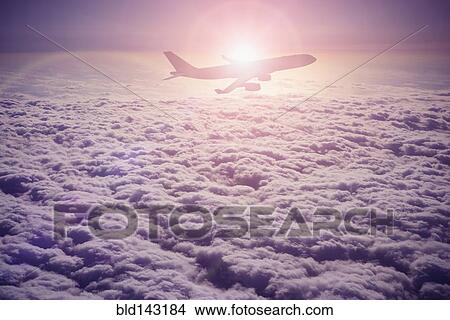 Picture - Silhouette of airplane flying over clouds. Fotosearch