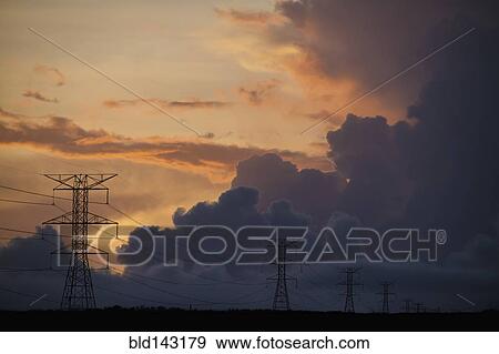 Stock Photo - Silhouette of power lines under cloudy sky. Fotosearch
