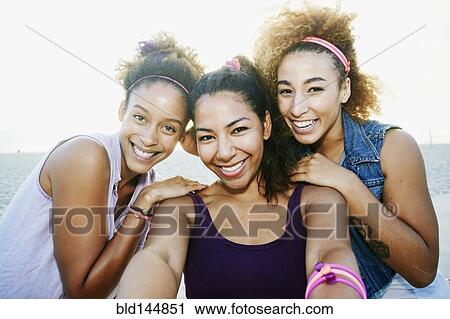 Stock Image - Smiling friends taking selfie at beach. Fotosearch