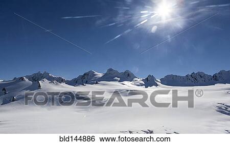 Snow covered mountain tops in remote landscape View Large Photo Image Stock Photograph - Snow covered mountain tops in remote landscape. Fotosearch