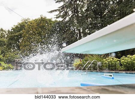 Stock Image - Splashing water near diving board in swimming pool. Fotosearch