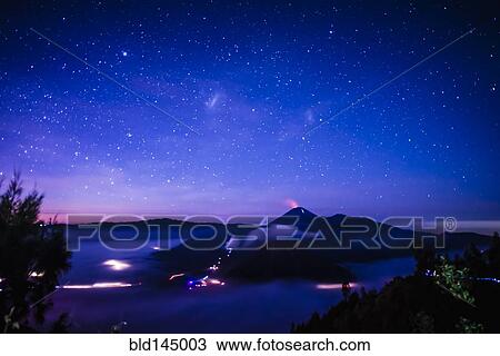 Stock Image - Starry night sky over active volcano. Fotosearch