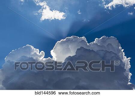 Sunbeams shining through clouds in blue sky View Large Photo Image Stock Photograph - Sunbeams shining through clouds in blue sky. Fotosearch