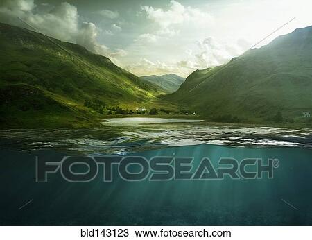 Stock Image - Sunbeams shining through surface of still remote lake. Fotosearch