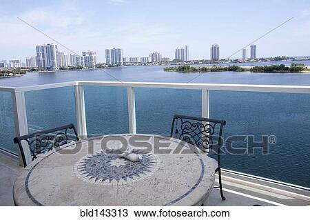 Stock Image - Table and chairs on balcony overlooking city skyline, Miami, Florida, United States. Fotosearch