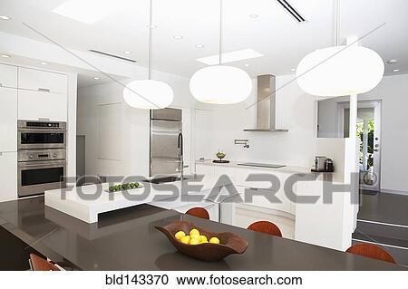 Stock Image - Table, countertops and light fixtures in modern kitchen. Fotosearch