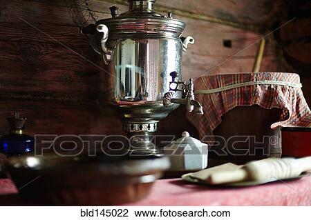 Stock Image - Tea dispenser and plates on table. Fotosearch