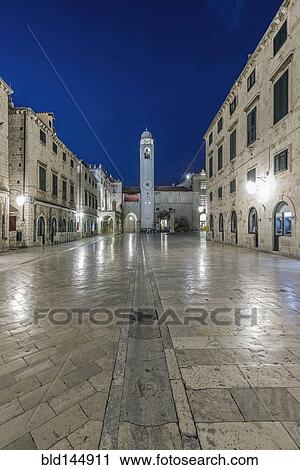 Stock Image - Town square, buildings and tower illuminated at night, Dubrovnik, Dubrovnik-Neretva, Croatia. Fotosearch