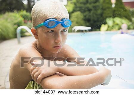 Stock Photo - Upset Caucasian boy sitting near swimming pool. Fotosearch