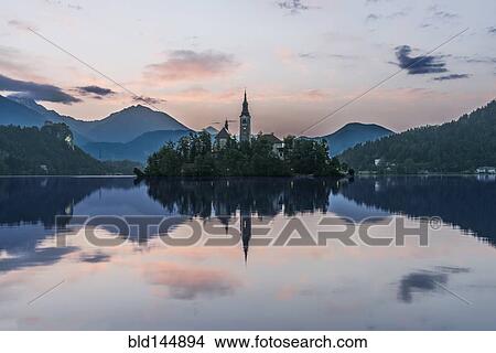 Picture - Village church and buildings reflected in still lake, Bled, Upper Carniola, Slovenia. Fotosearch