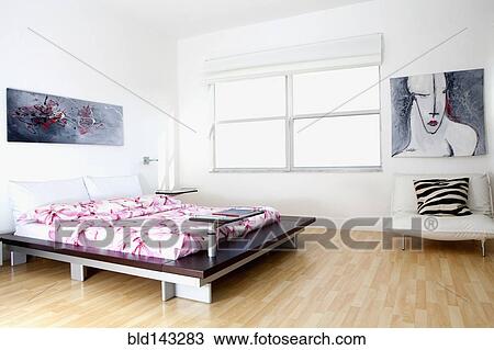 Stock Image - Wall art, bed and windows in modern bedroom. Fotosearch