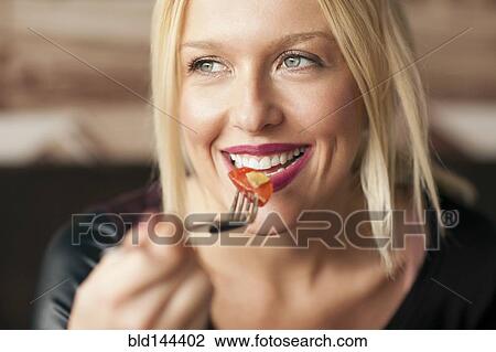 Stock Image - Woman eating food in cafe. Fotosearch