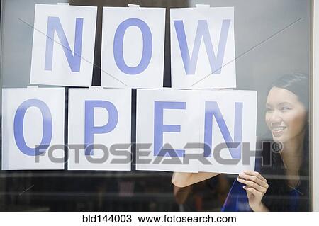 Woman hanging now open sign in store window View Large Photo Image Stock Image - Woman hanging now open sign in store window. Fotosearch