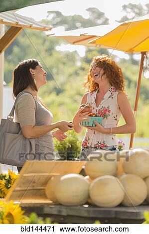 Stock Image - Woman laughing at farmers market. Fotosearch