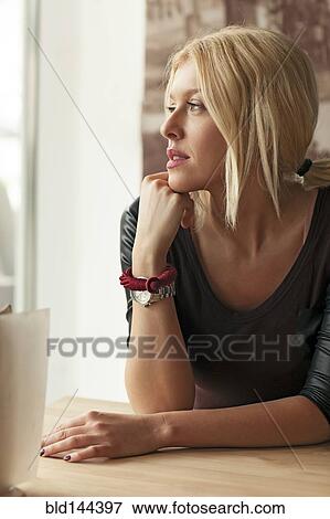 Stock Photo - Woman sitting alone at table in cafe. Fotosearch