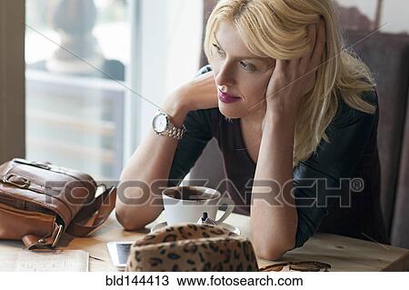 Stock Image - Woman sitting alone in cafe. Fotosearch