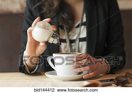 Woman sprinkling sugar in coffee in cafe View Large Photo Image Stock Image - Woman sprinkling sugar in coffee in cafe. Fotosearch