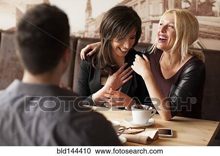 Stock Image - Women laughing in cafe. Fotosearch
