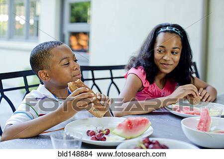 Picture - African American children eating lunch outdoors. Fotosearch
