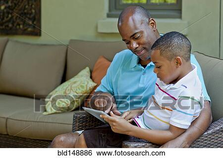 African American father and son using digital tablet View Large Photo Image Stock Photograph - African American father and son using digital tablet. Fotosearch
