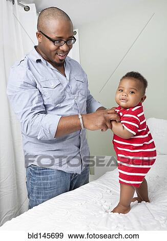 African American father helping baby son to stand up View Large Photo Image Stock Photo - African American father helping baby son to stand up. Fotosearch