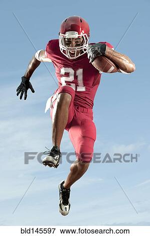 Stock Photo - African American football player running with football. Fotosearch