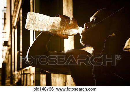 Stock Photograph - African American man drinking water after exercise. Fotosearch
