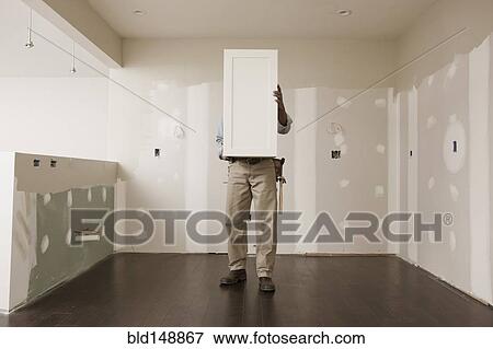 African American man holding cabinet door in unfinished room View Large Photo Image Stock Photo - African American man holding cabinet door in unfinished room. Fotosearch
