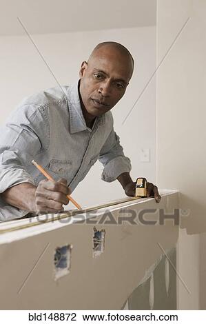 African American man measuring wall in unfinished room View Large Photo Image Stock Image - African American man measuring wall in unfinished room. Fotosearch