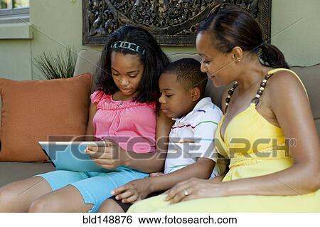 Stock Photograph - African American mother watching children with digital tablet. Fotosearch