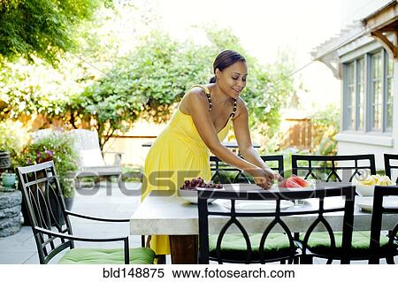 Stock Photography - African American woman preparing lunch on patio. Fotosearch