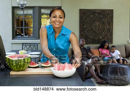Picture - African American woman preparing watermelon. Fotosearch
