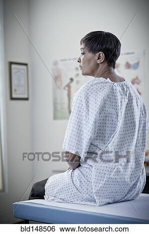 Stock Photograph - African American woman waiting in examination room. Fotosearch