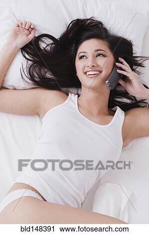 Alluring mixed race woman laying in bed talking on telephone View Large Photo Image Stock Image - Alluring mixed race woman laying in bed talking on telephone. Fotosearch