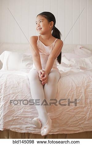 Stock Photo - Asian girl in ballet costume sitting on bed. Fotosearch