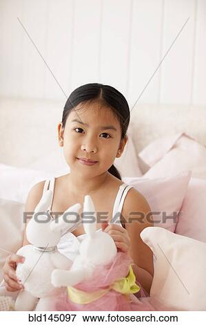 Asian girl on bed holding stuffed rabbits View Large Photo Image Stock Photo - Asian girl on bed holding stuffed rabbits. Fotosearch