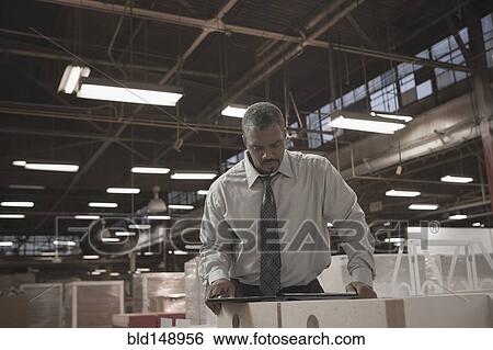 Stock Photograph - Black businessman working in warehouse. Fotosearch