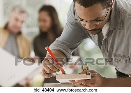 Picture - Black carpenter measuring lumber. Fotosearch